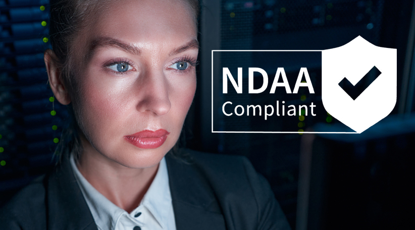 Eine weibliche Administratorin schaut in einen Monitor. Daneben sieht man das Logo von "NDAA Complient"